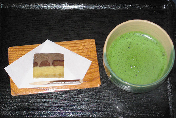 Bowl of matcha and layered Japanese sweet served on a black tray at Kosoan
