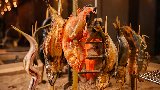 Whole fish roasting upright beside charcoal at Robatayaki HOTARU