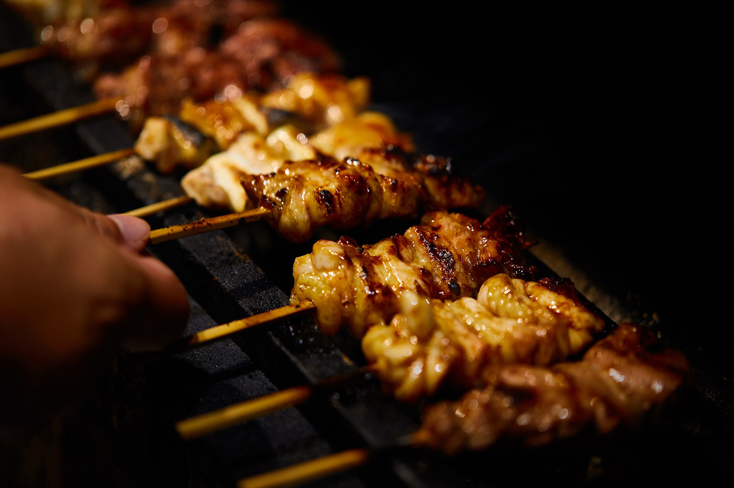 Yakitori skewers grilling over charcoal at Yakitoriya Tera