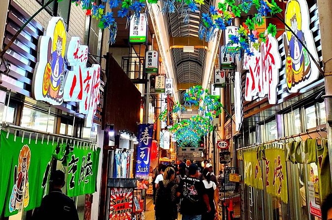 Travelers moving through a colorful Osaka food arcade on the selected tour