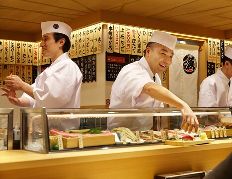 Sushi chefs working behind the standing counter at Uogashi Nihon-Ichi in ecute Shinagawa