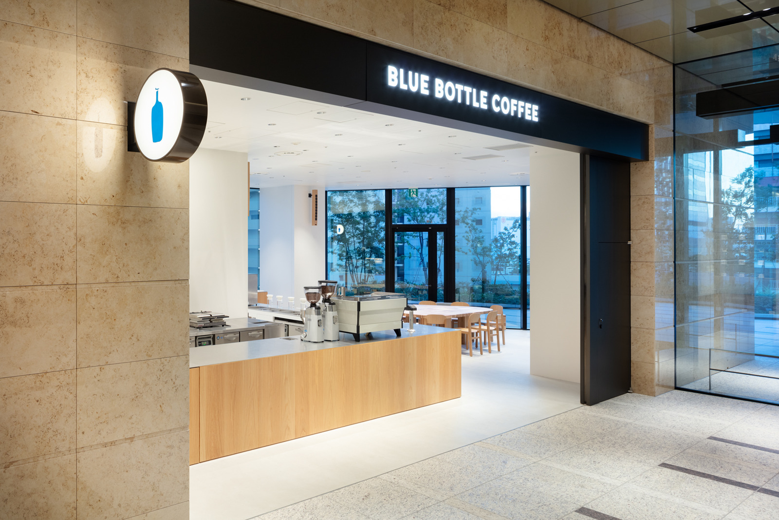 Blue Bottle Coffee Takeshiba entrance with its sign, pale wood counter and bright seating