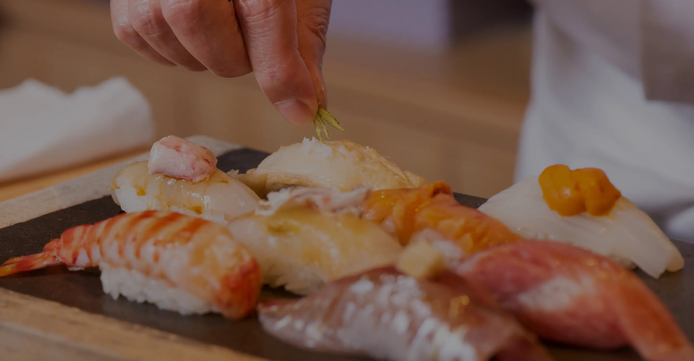 Sushi chef finishing several pieces of sushi at Tsukiji Aozora Sandaime